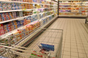 Un caddie dans une allée de supermarché au rayon yaourt