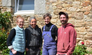 Trois femmes et un homme posent devant une maison en pierre