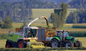 Un chantier d'ensilage d'herbe avec une ensileuse et un tracteur avec remorque