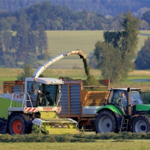 Un chantier d'ensilage d'herbe avec une ensileuse et un tracteur avec remorque