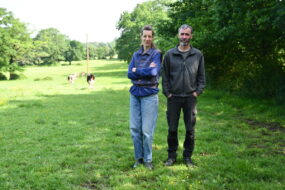 un homme et une femme sur un pâturage avec des haies à côté