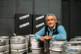 Un homme pose au milieu de fûts de bière Coreff
