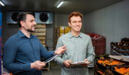 Deux hommes souriants discutent dans une chambre froide remplie de légumes