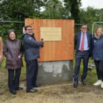 Un groupe de personne devant la première planche posée d'un bâtiment en construction