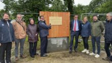 Un groupe de personne devant la première planche posée d'un bâtiment en construction