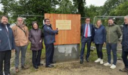 Un groupe de personne devant la première planche posée d'un bâtiment en construction