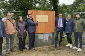 Un groupe de personne devant la première planche posée d'un bâtiment en construction