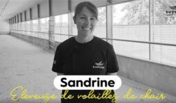 Portrait d'une jeune femme souriante dans un bâtiment d'élevage de volailles vide