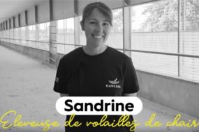 Portrait d'une jeune femme souriante dans un bâtiment d'élevage de volailles vide