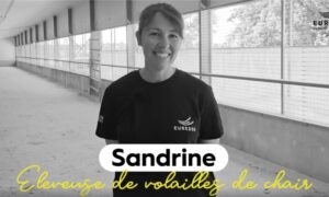 Portrait d'une jeune femme souriante dans un bâtiment d'élevage de volailles vide