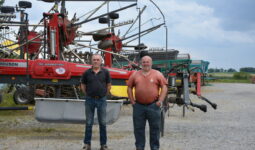 Deux agriculteurs devant du matériel dans une cour