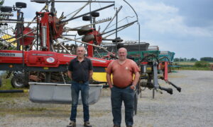 Deux agriculteurs devant du matériel dans une cour
