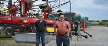 Deux agriculteurs devant du matériel dans une cour