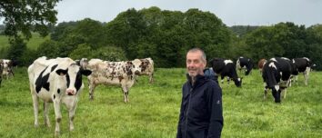 Un éleveur souriant au milieu d'un troupeau de vaches laitières au pâturage