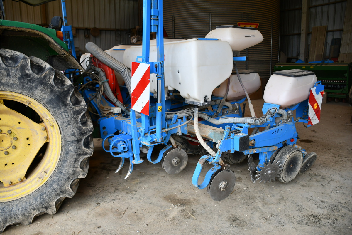 Les dents flexibles grattent la terre derrière les roues du tracteur.