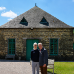 Un homme et une femme devant un bâtiment en pierre rénové