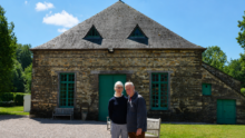 Un homme et une femme devant un bâtiment en pierre rénové