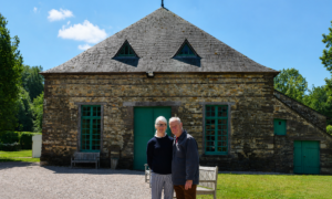 Un homme et une femme devant un bâtiment en pierre rénové