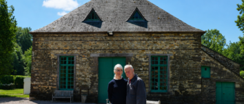 Un homme et une femme devant un bâtiment en pierre rénové