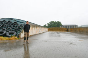 un homme devant des silos de maïs