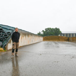 un homme devant des silos de maïs