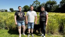 deux agriculteurs et une technicienne devant un champ d'orge