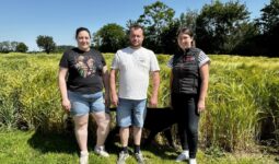 deux agriculteurs et une technicienne devant un champ d'orge