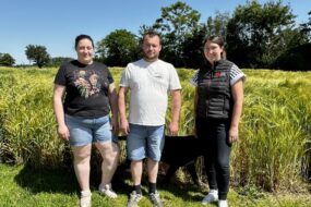 deux agriculteurs et une technicienne devant un champ d'orge