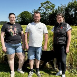deux agriculteurs et une technicienne devant un champ d'orge