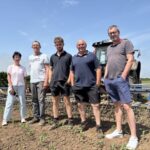 Un groupe de personnes dans un champ devant un tracteur
