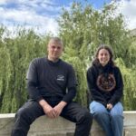 Un homme et une femme assis sur un mur devant un saule pleureur