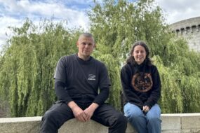Un homme et une femme assis sur un mur devant un saule pleureur