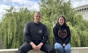 Un homme et une femme assis sur un mur devant un saule pleureur