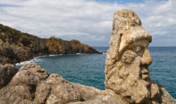 Un visage avec un bonnet sculpté sur rocher en bord de mer