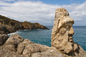 Un visage avec un bonnet sculpté sur rocher en bord de mer