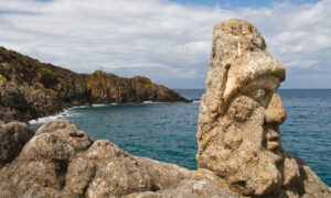 Un visage avec un bonnet sculpté sur rocher en bord de mer