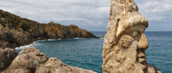 Un visage avec un bonnet sculpté sur rocher en bord de mer