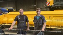 Deux hommes devant une moissoneuse dans un atelier