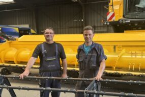 Deux hommes devant une moissoneuse dans un atelier