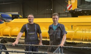 Deux hommes devant une moissoneuse dans un atelier
