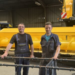 Deux hommes devant une moissoneuse dans un atelier