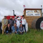 Un groupe de gens et une mascotte de vache devant uns tructure