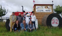 Un groupe de gens et une mascotte de vache devant uns tructure