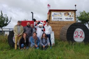 Un groupe de gens et une mascotte de vache devant uns tructure