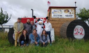 Un groupe de gens et une mascotte de vache devant uns tructure