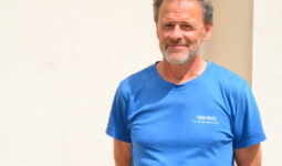 Un homme avec un T-shirt bleu et les bras croisés dans le dos