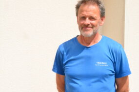 Un homme avec un T-shirt bleu et les bras croisés dans le dos