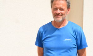 Un homme avec un T-shirt bleu et les bras croisés dans le dos