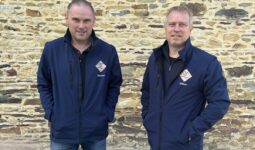 Deux hommes devant un mur de pierre
