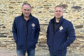 Deux hommes devant un mur de pierre